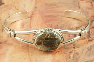 Genuine Sunnyside Turquoise set in Sterling Silver Bracelet. The matrix on this rare stone is outstanding. The Sunnyside mine is located in northern Nevada near the town of Tuscarora in the Tuscarora mountain range. The mine is no longer in operation as it has become part of a gold mining operation and a privately owned ranch. The Sunnyside mine was mined mostly in the 70's. You won't find much of this great turquoise around anymore except for old stashes. Created by Navajo Artist Flora Willeto. signed.